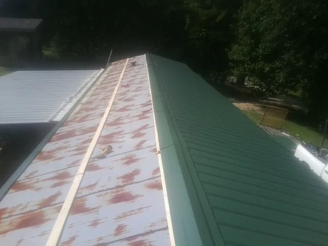 Old rusted panels beside newly installed green metal roofing — Wind Damage Roof Repair by Roofing Brothers in Foresthill