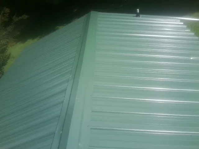New green metal panels meeting at the ridge of a roof — Flat Roof Repair work by our crew in Foresthill