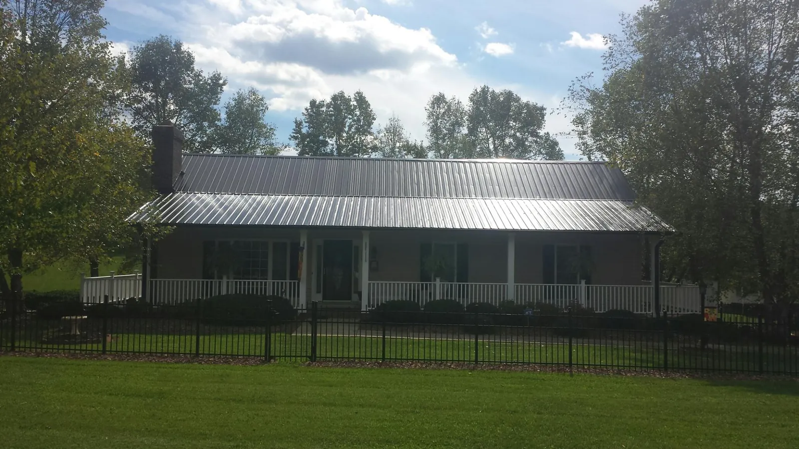 Gray metal roof on a brick ranch with a full width front porch — Gutter Guard Installation work by our crew in Foresthill