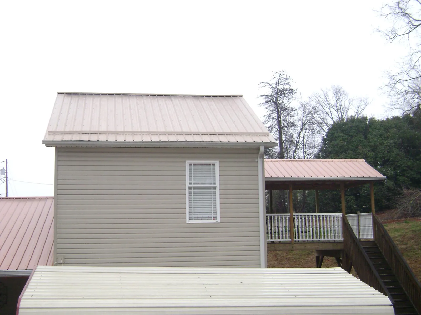 Tan metal roofs on a two story addition and attached porch, from a Roof Replacement job in Foresthill