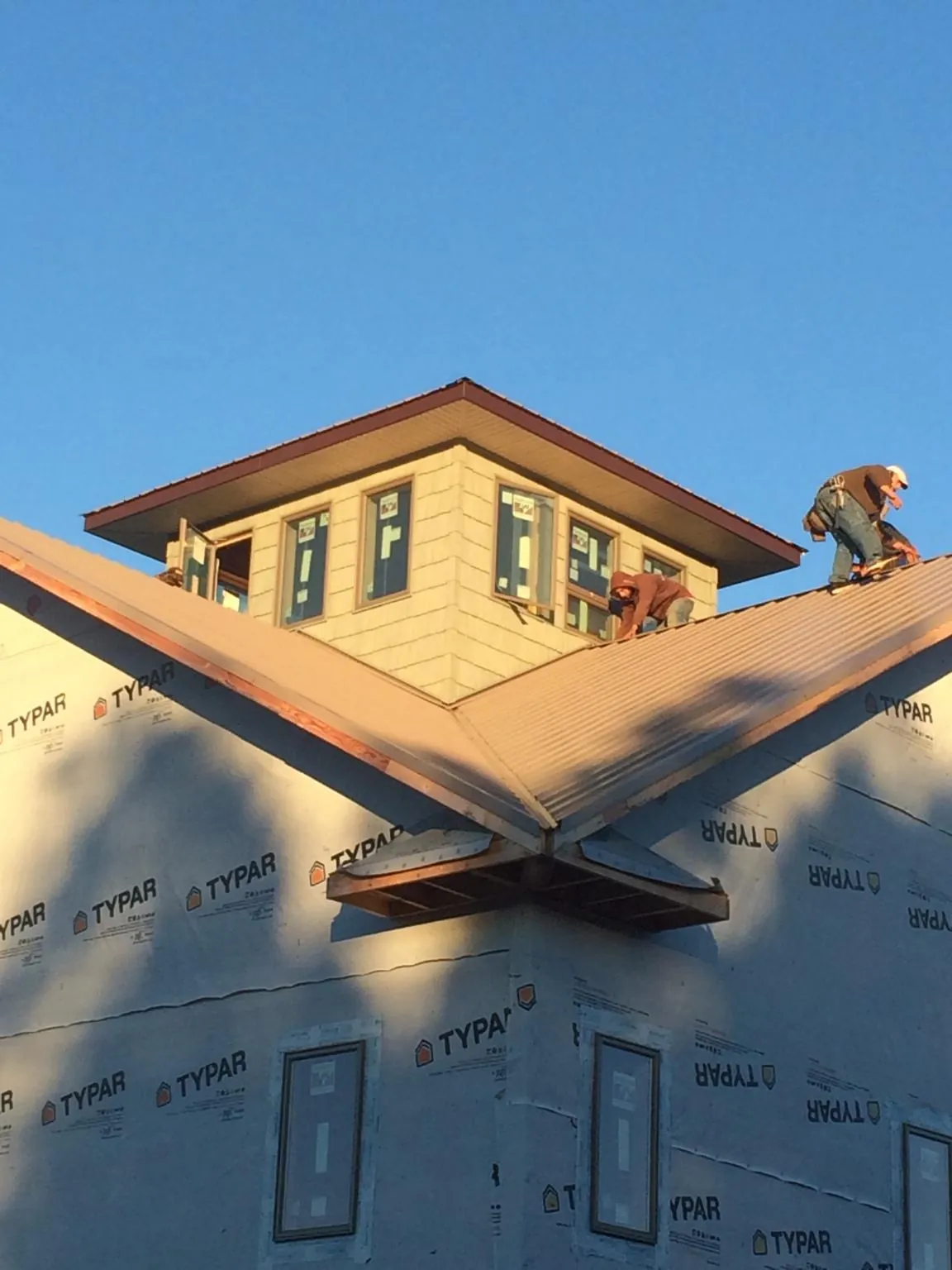 Roofers working around a rooftop cupola on a new metal roof at sunset — Roof Waterproofing in Foresthill by Roofing Brothers